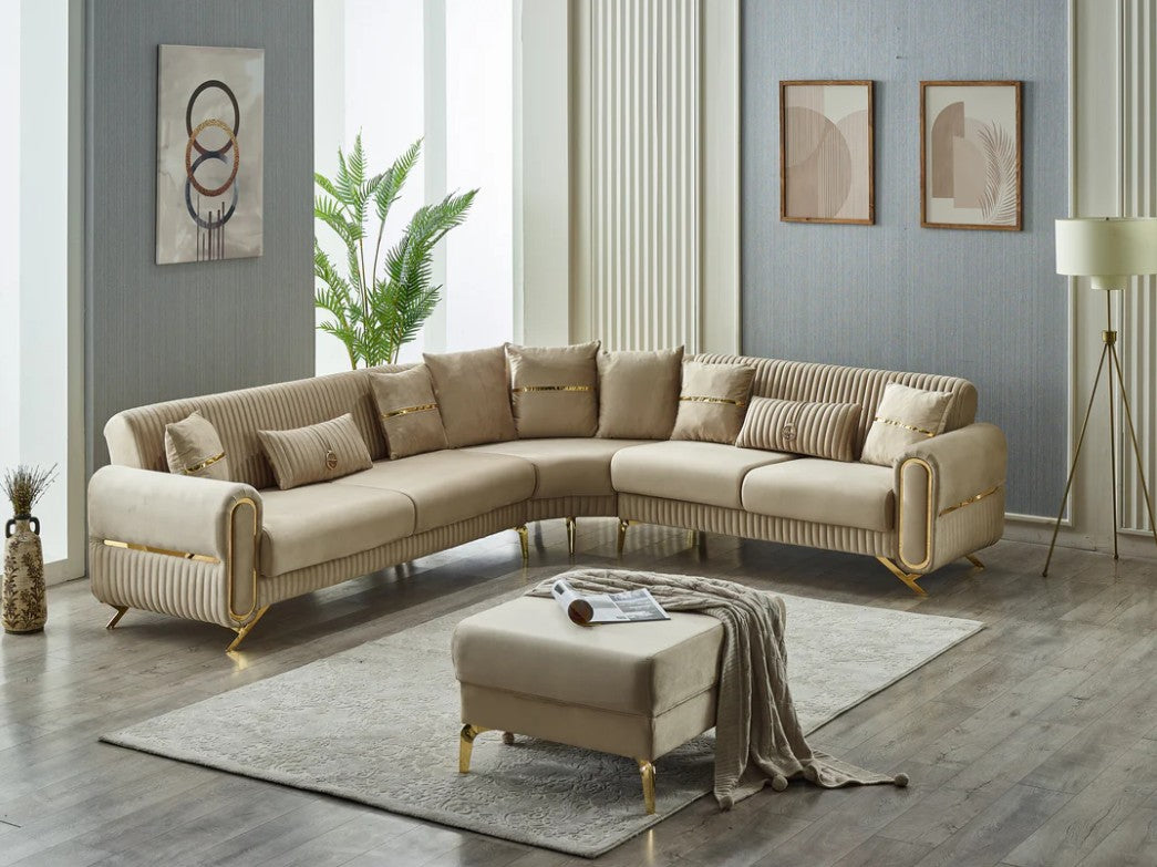 Beige velvet sectional sofa with gold legs and matching ottoman in a modern living room