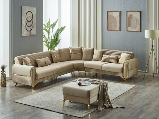 Beige velvet sectional sofa with gold legs and matching ottoman in a modern living room